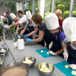 Dzieci podczas zajęć kulinarnych, a głowach mająbiałe czapki kucharskie