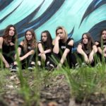 Wykonawczynie zespołu siedzące na tle muralu