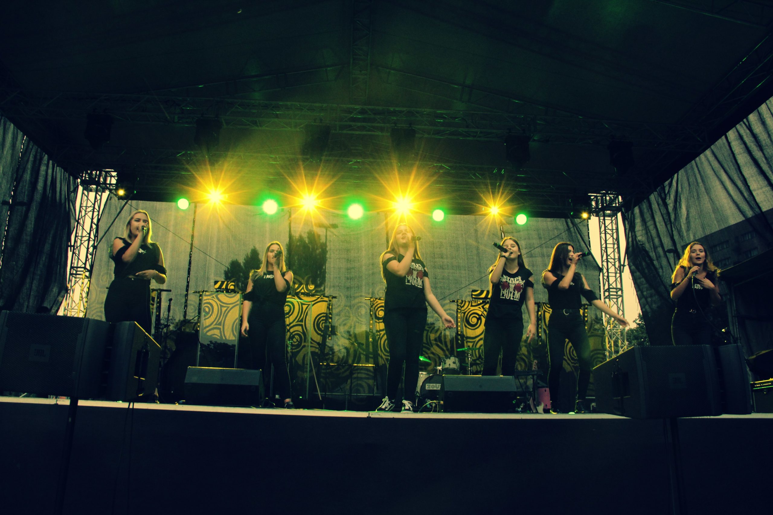 Wieczorny występ zespołu Prink Girls - wykonawcy na podświetlonej scenie