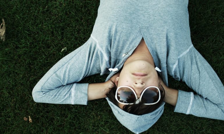 młody chłopiec leży na trawie z rękami pod głową