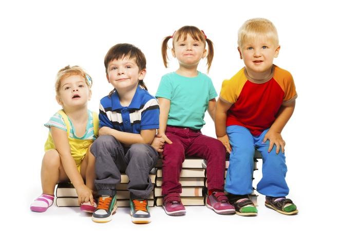 zdjęcie czworga małych dzieci siedzących na książkach