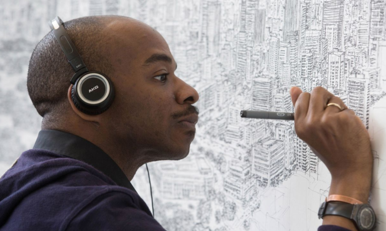 mężczyzna w słuchawkach malujący obraz na ścianie