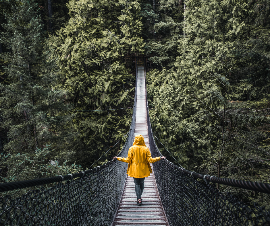 człowiek idący po moście linowym na tle drzew