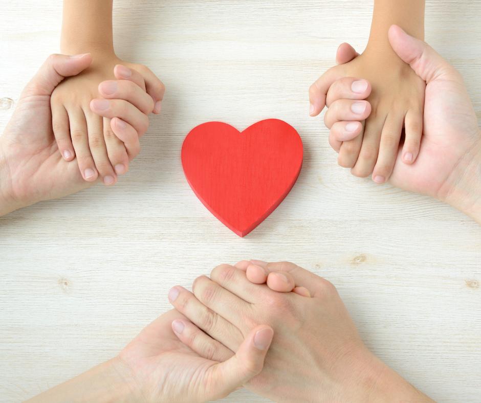 trzymające się ręce rodziców i dziecka dookoła wyrzeźbionego serca