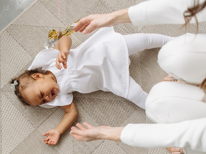 Matka wyciągająca ręce do płaczącego niemowlaka