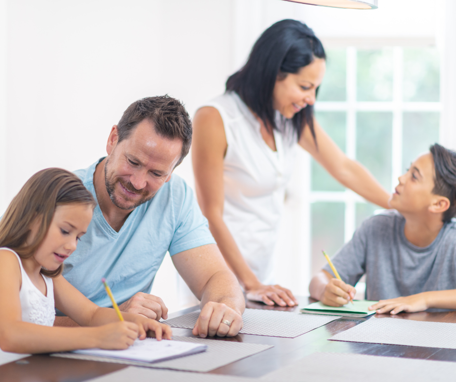 Rodzina przy biurku. Rodzice pomagają dzieciom prze pracy. Dzieci piszą ołówkami