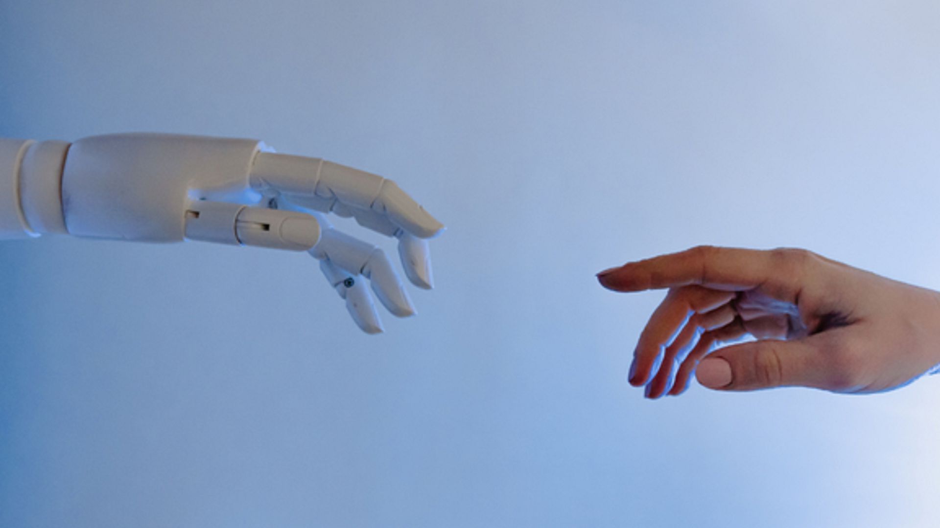 fotografia przedstawia dłoń robota i ludzką dłoń.